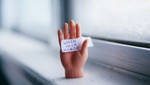 hand holding sign saying "wash your hands"